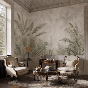 May include: A room featuring a wall mural with a muted green and beige tropical palm leaf pattern. The space includes two cream-colored upholstered armchairs with wooden frames, a dark wood coffee table, and a matching side table with a lamp.