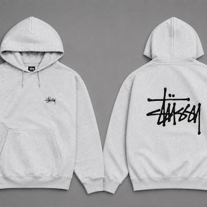 May include: A light gray hooded sweatshirt featuring a black Stüssy logo on the left chest and a large black Stüssy logo printed on the back. The hoodie includes a front kangaroo pocket, long sleeves with ribbed cuffs, and a matching drawstring hood.