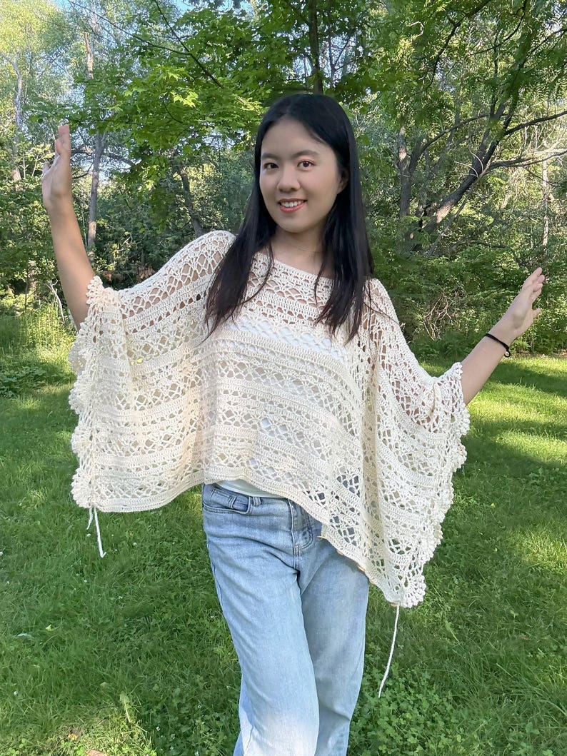 Pu&ograve; includere: Un poncho all'uncinetto color bianco sporco caratterizzato da un intricato motivo traforato con fasce orizzontali a maglia piena e un bordo smerlato. Il capo presenta una vestibilit&agrave; ampia con scollo a barchetta e delicati laccetti laterali.