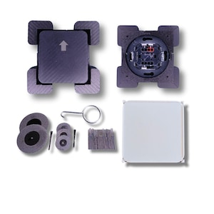 May include: A collection of electrical components, including a dark grey square cover with an arrow, a light switch, and various small grey circular and rectangular parts. The components are arranged on a white background.