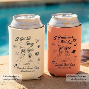 Puede incluir: Dos enfriadores de latas de bebidas, uno marfil y otro naranja, con texto e ilustraciones en negro. El enfriador marfil dice "A tini bit tipsy" y el enfriador naranja dice "A Bride in a tini bit". Ambos dicen "Camila's Bach Club Miami Beach, FL".