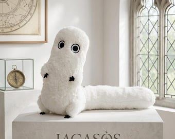 May include: A white plush toy with a long, cylindrical body and a rounded head. It features two large, circular black and white eyes and small black hands and feet. The word LAGASOS is printed in black on the front of the white pedestal base.