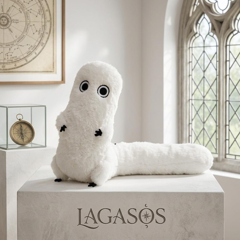 May include: A white plush toy with a long, cylindrical body and a rounded head. It features two large, circular black and white eyes and small black hands and feet. The word LAGASOS is printed in black on the front of the white pedestal base.