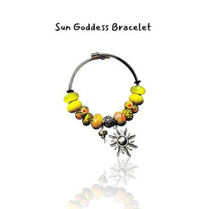 May include: A bracelet with the text "Sun Goddess Bracelet". The bracelet features yellow and orange beads, a silver charm with a sun design, and a silver-colored metal band.