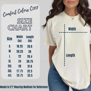 Pu&ograve; includere: T-shirt color crema Comfort Colors C1717 con tabella taglie. La tabella elenca le taglie dalla S alla 4XL, con misure di larghezza e lunghezza in pollici. La modella &egrave; alta 1,57 m e indossa una taglia M come riferimento.