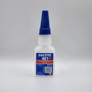 May include: A white bottle of Loctite 401 instant adhesive with a blue cap. The label features the Loctite logo and product information. The bottle contains 20g of adhesive.