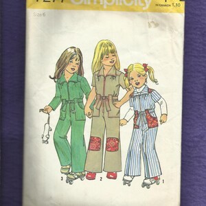 May include: Simplicity sewing pattern 7277, size 6, featuring illustrations of three girls in jumpsuits and roller skates. The jumpsuits are in green, tan, and blue striped patterns. The pattern includes a price tag.