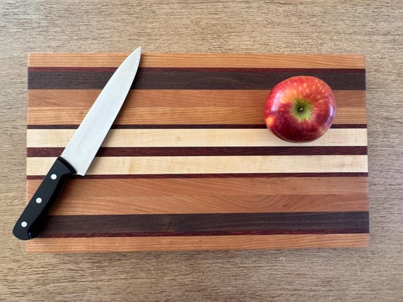 Four-wood edge-grain butcherblock (cherry, walnut, maple, AND the rare orange pop of padauk) makes this a functional sculpture that belongs on a cheeseboard spread.