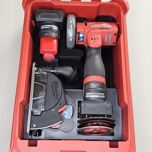 May include: A red Milwaukee tool case with a clear lid, containing a red and black power tool, battery, and cutting discs. The case is open, revealing the organized interior with various tools and accessories.