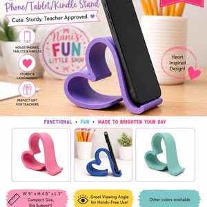 May include: A purple heart-shaped stand for phones, tablets, and Kindles. The stand features a curved, open design that supports a device at an angle. Text on the image includes "HEART Phone/Tablet/Kindle Stand" and dimensions of W 12.7 cm x H 11.4 cm x L 7.6 cm.