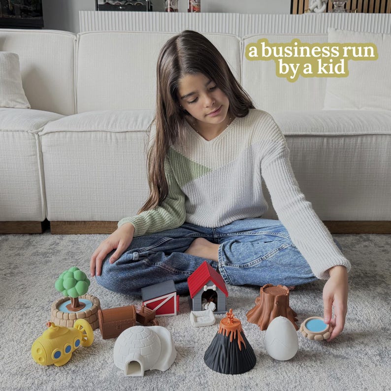 May include: A young person sits surrounded by colorful toy structures, including a yellow submarine, a red dog house, a brown tree stump, and a white igloo. The text "a business run by a kid" is in the background.