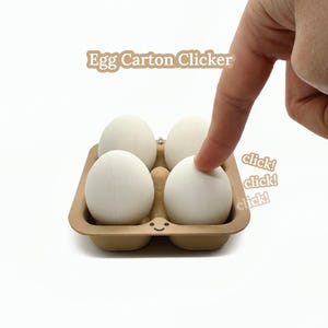 May include: A brown egg carton holding four white eggs. The text "Egg Carton Clicker" is above the carton. A finger presses an egg. The word "click!" is repeated three times.