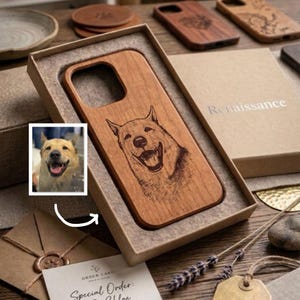 Op de afbeelding: Een houten telefoonhoesje met een lasergegraveerd portret van een lachende hond, gepresenteerd in een kartonnen geschenkdoos. Het hoesje heeft een uitsparing voor de cameralens en wordt getoond naast een kleine foto van de hond.