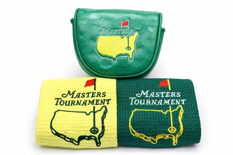 Puede incluir: Funda verde para la cabeza del palo de golf y dos toallas de golf. La funda y las toallas presentan el logotipo del Masters Tournament, que incluye una bandera roja, la palabra "Masters" y un mapa del campo en amarillo y verde.