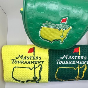 Puede incluir: Funda verde para la cabeza del palo de golf y dos toallas de golf. La funda tiene la palabra "Masters" y un mapa del campo de golf bordado. Las toallas son amarillas y verdes, con las palabras "Masters Tournament" y un mapa del campo.