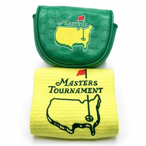 May include: Green golf club head cover and yellow golf towel. The head cover features the Masters logo and a red flag. The towel displays the Masters Tournament logo and a map of the course.