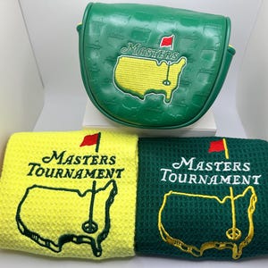 Puede incluir: Funda de putter de golf verde y dos toallas de golf. La funda del putter es verde con el logotipo de Masters bordado. Las toallas son amarillas y verdes, cada una con el logotipo de Masters Tournament bordado en blanco y dorado.