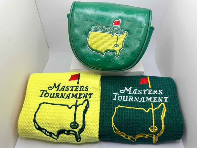 Puede incluir: Funda de putter de golf verde y dos toallas de golf. La funda del putter es verde con el logotipo de Masters bordado. Las toallas son amarillas y verdes, cada una con el logotipo de Masters Tournament bordado en blanco y dorado.