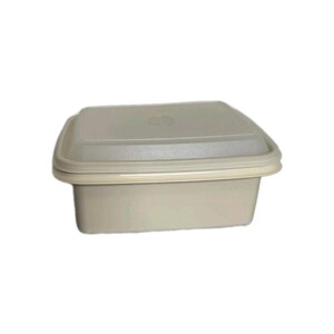 May include: A beige square food storage container with a matching lid. The container has a slightly textured surface and a rounded edge. The lid fits snugly on top, creating an airtight seal. Ideal for storing leftovers or meal prepping.