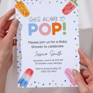 Puede incluir: Invitación a un baby shower con el texto "SHES READY TO POP!" e ilustraciones de paletas de hielo coloridas. La invitación incluye detalles del evento, como la fecha, la hora, el lugar y la información de confirmación de asistencia.