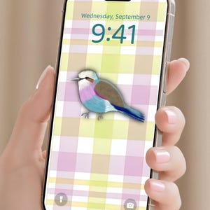 May include: A smartphone displaying a lock screen with a pastel plaid background in yellow, pink, and white. The screen shows the time 9:41 and the date Wednesday, September 9, with a central illustration of a bird featuring brown, pink, and blue feathers.