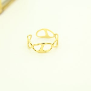May include: A gold-toned ring with a unique, abstract design. The ring is made of a single piece of metal that is twisted and shaped into a series of overlapping circles.