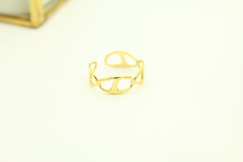 May include: A gold-toned ring with a unique, abstract design. The ring is made of a single piece of metal that is twisted and shaped into a series of overlapping circles.
