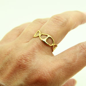 May include: A gold ring with a unique, open design featuring a series of connected ovals.