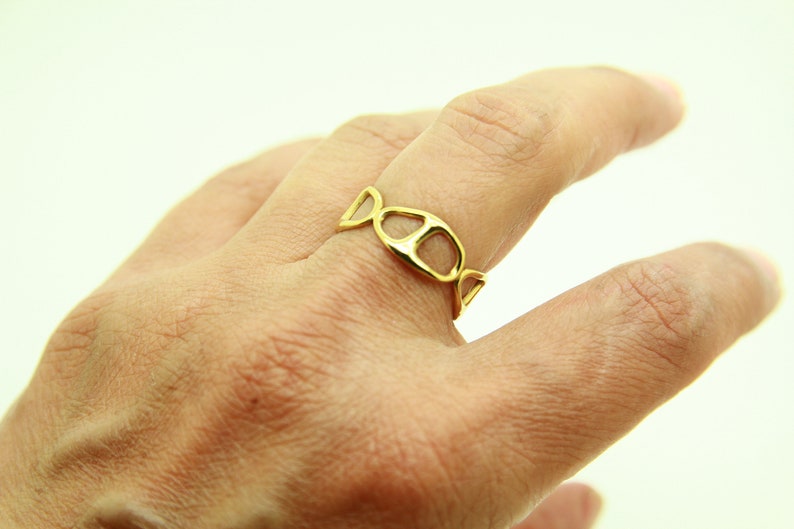 May include: A gold ring with a unique, open design featuring a series of connected ovals.
