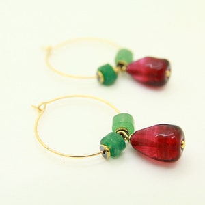 May include: Gold hoop earrings with a dangling red glass teardrop and green glass beads.