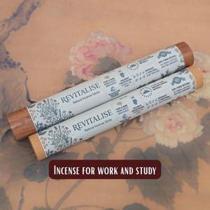 May include: Two cylindrical incense stick packages with wooden ends. The packages are light blue with the word "REVITALISE" and the text "Natural Incense Sticks". The text "INCENSE FOR WORK AND STUDY" is at the bottom.