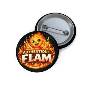 Peut inclure: Un bouton rond noir avec un personnage de flamme de dessin animé faisant un signe de pouce. Le texte "AUTHENTIQUE FLAM" est affiché en lettres dorées, entouré de flammes orange et jaunes.