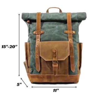 May include: A roll-top backpack made of dark green canvas and brown leather accents. It features two vertical leather straps, a front pocket with a buckle closure, and side pockets. Dimensions are 15-20 inches in height, 11 inches in width, and 5 inches in depth.