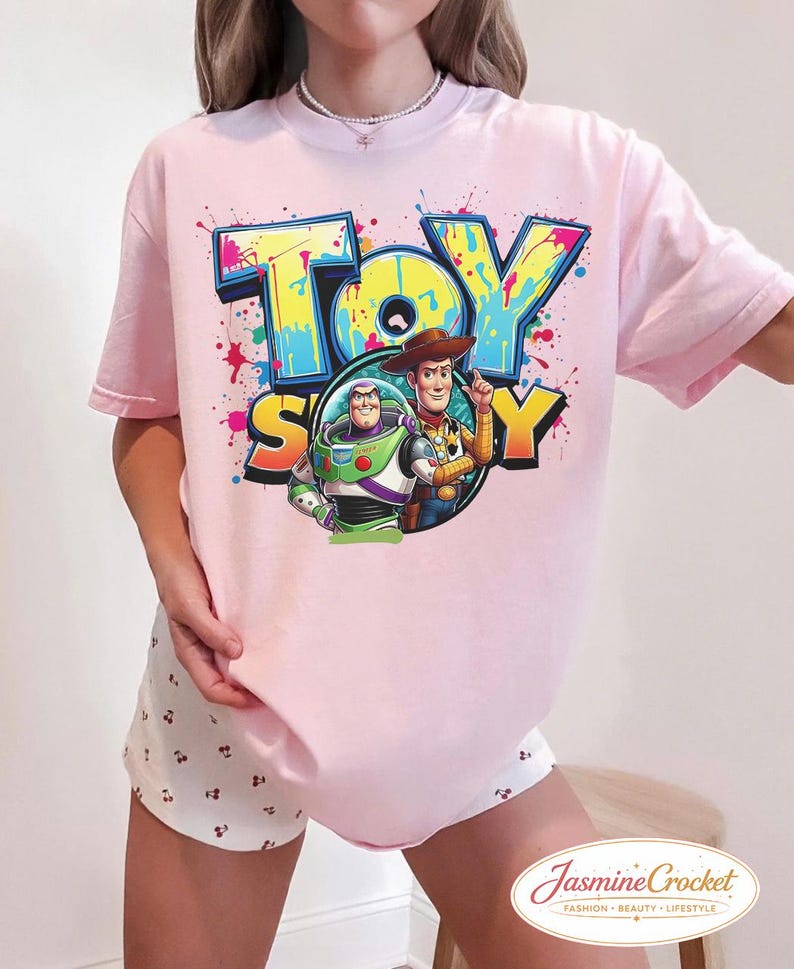 Puede incluir: Camiseta rosa claro con la inscripci&oacute;n "TOY STORY" en un estilo graffiti colorido. El dise&ntilde;o incluye a Buzz Lightyear y Woody. La camiseta de manga corta tiene un corte holgado, ideal para un look casual.