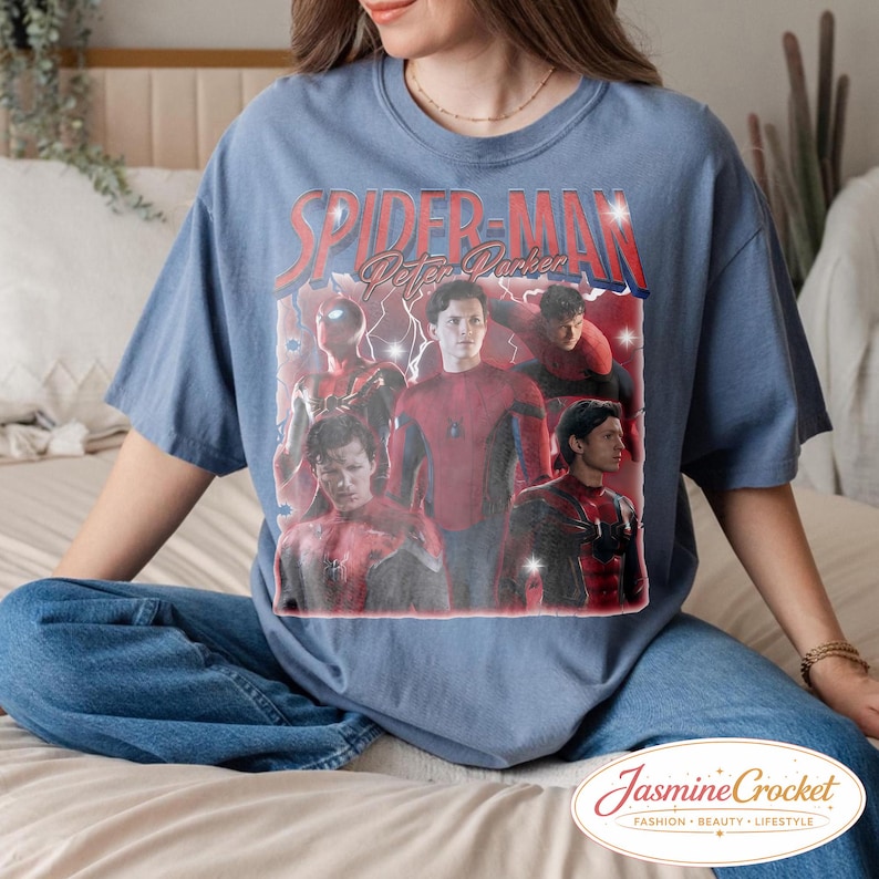 以下が含まれることがあります： スパイダーマンのグラフィックと「SPIDER-MAN Peter Parker」の文字が入った青い半袖Tシャツ。グラフィックには、さまざまなポーズのスパイダーマンの画像が含まれています。このシャツはJasmine Crocket製です。