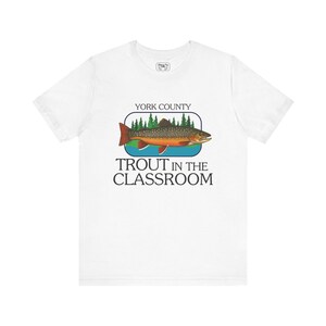 May include: White t-shirt featuring a colorful illustration of a trout fish with the text "York County Trout in the Classroom". The design includes a fish, trees, and water, creating a nature-themed graphic.