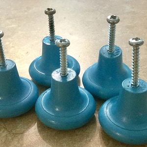 May include: Five blue plastic cabinet knobs with silver screws. The knobs are round with a raised edge and a slightly indented center.