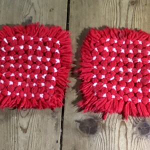 May include: Two red and white crocheted pot holders with a fringe border.