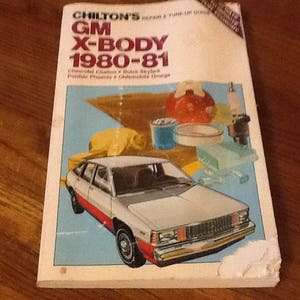 May include: A vintage book cover for a car repair manual titled "Chilton's GM X-Body 1980-81". The cover features a white car with red trim and a blue background.