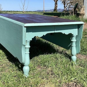 May include: A teal blue drop leaf table with a dark wood top. The table has turned legs with a decorative carved design.