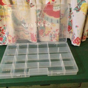 May include: A clear plastic storage box with a lid. The box has 16 compartments and the lid has the word "OH-14574" printed on it.