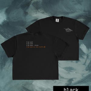 Puede incluir: Camisetas negras con texto blanco y un gr&aacute;fico de monta&ntilde;a. Una camiseta muestra el texto "$ gh push", "$ gh push --force" y "$ gh push me into traffic". La otra camiseta tiene un gr&aacute;fico de monta&ntilde;a y la palabra "devtribe".