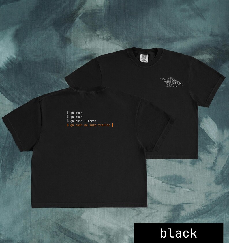 Puede incluir: Camisetas negras con texto blanco y un gr&aacute;fico de monta&ntilde;a. Una camiseta muestra el texto "$ gh push", "$ gh push --force" y "$ gh push me into traffic". La otra camiseta tiene un gr&aacute;fico de monta&ntilde;a y la palabra "devtribe".