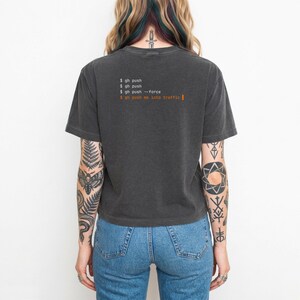 Puede incluir: Camiseta gris oscuro con el texto "$ gh push" y "$ gh push me into traffic" en naranja. Una prenda de vestir informal.