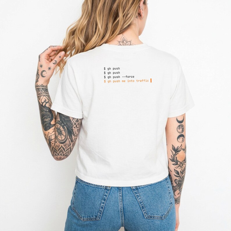 Puede incluir: Camiseta blanca corta con texto naranja "$ gh push". El texto se repite, las &uacute;ltimas l&iacute;neas dicen "$ gh push --force" y "$ gh push me into traffic". La camiseta se lleva con unos vaqueros azules.