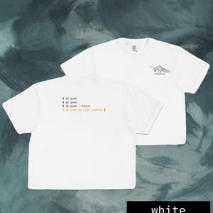 Puede incluir: Dos camisetas blancas. Una camiseta tiene el texto "$ gh push, $ gh push, $ gh push --force, $ gh push me into traffic" en naranja. La otra camiseta tiene un gr&aacute;fico de monta&ntilde;a y el texto "-dode vibe" en negro.
