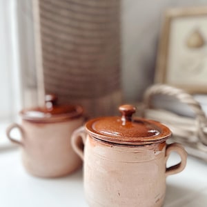 May include: A set of three ceramic mugs with a speckled, matte finish. The mugs are in shades of cream, light grey, and dark grey. Each mug has a simple, minimalist design, ideal for coffee or tea.