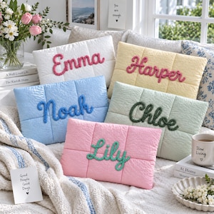 May include: Five rectangular quilted throw pillows in white, yellow, light blue, sage green, and pink. Each pillow features a name embroidered in a thick, textured yarn script: Emma, Harper, Noah, Chloe, and Lily, centered on the front panel.