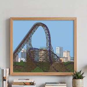 Könnte beinhalten: Ein gerahmter Kunstdruck mit einer detaillierten Illustration einer Holzachterbahn mit violetten Schienen vor einem hellblauen Himmel. Die braune, komplexe Struktur der Achterbahn ist vor einer Kulisse aus Gebäuden und grünen Bäumen dargestellt.