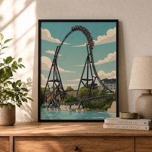 Könnte beinhalten: Ein gerahmter Kunstdruck, der eine schwarze Achterbahn mit einem Zug voller Fahrgäste am höchsten Punkt eines steilen Abfalls zeigt. Die Szene umfasst einen hellblauen Himmel mit weißen Wolken, grüne Bäume und ein Gewässer unter der Konstruktion.